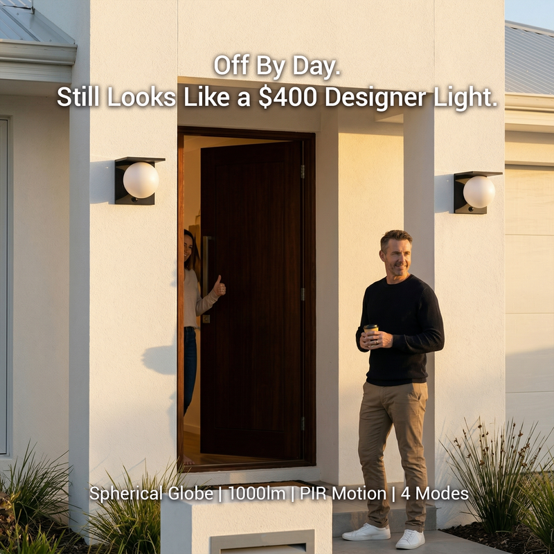 Lumora Solar globe wall lights installed either side of modern front door at golden hour, man holding coffee smiling outside, woman giving thumbs up from doorway, text overlay: Off By Day. Still Looks Like a $400 Designer Light.
