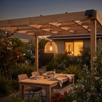 PT0913 solar rattan pendant glowing over wooden pergola dining table at dusk, surrounded by native Australian plants — warm 3000K light enhances outdoor entertaining with IP54 weatherproof design.