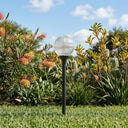 Garden light fixture in a grassy area with plants and flowers