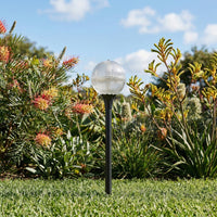 Garden light fixture in a grassy area with plants and flowers