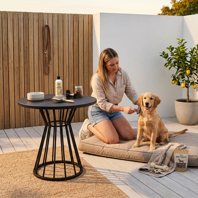 Woman sitting on a patio with a dog, surrounded by outdoor furniture and decor.