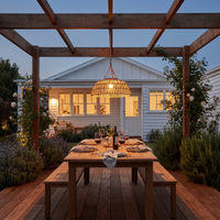 PT0901 Haiku Solar Rattan Hanging Lantern suspended from a wooden pergola over an outdoor dining table, showcasing its handwoven PE rattan shade and natural hemp rope, ideal for coastal or boho garden aesthetics.