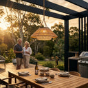 HAIKU Bamboo Garden Light PT0902 hanging in an outdoor pergola at sunset, illuminating a wooden dining table with warm light, creating a cozy evening atmosphere.