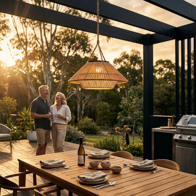 HAIKU Bamboo Garden Light PT0902 hanging in an outdoor pergola at sunset, illuminating a wooden dining table with warm light, creating a cozy evening atmosphere.
