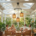 People sitting in a sunroom with large windows, plants, and decorative lights.