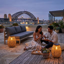 Couple enjoying romantic dinner on rooftop terrace at dusk with PT0906 solar handwoven garden lights, Sydney Harbour Bridge view, warm 3000K glow, outdoor solar lighting for alfresco dining