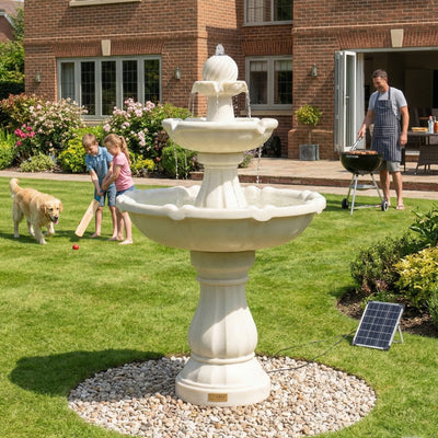 Three-tiered stone fountain in a garden with children playing and a man grilling.