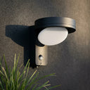 Serra solar wall light with PIR motion sensor mounted on textured grey wall, dark anthracite finish with white oval diffuser