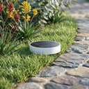 Niteo Circle Solar Light flush mounted on green lawn, modern round solar ground light with glass top, outdoor garden landscape lighting.