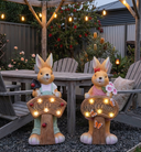 Solar rabbit ornament glowing at night in flower bed — warm LED auto dusk-to-dawn