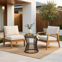 Two wooden chairs with white cushions and a small black table on a patio area.