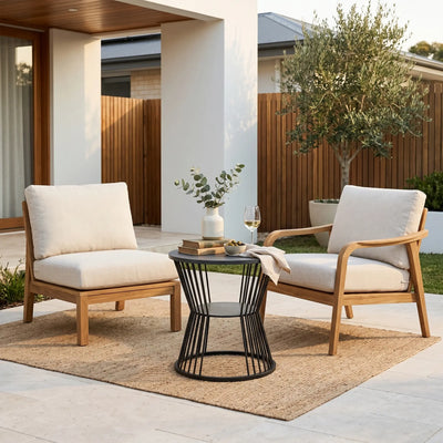 Two wooden chairs with white cushions and a small black table on a patio area.
