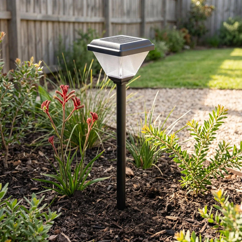 Solar-powered garden light in a garden setting with plants and grass.