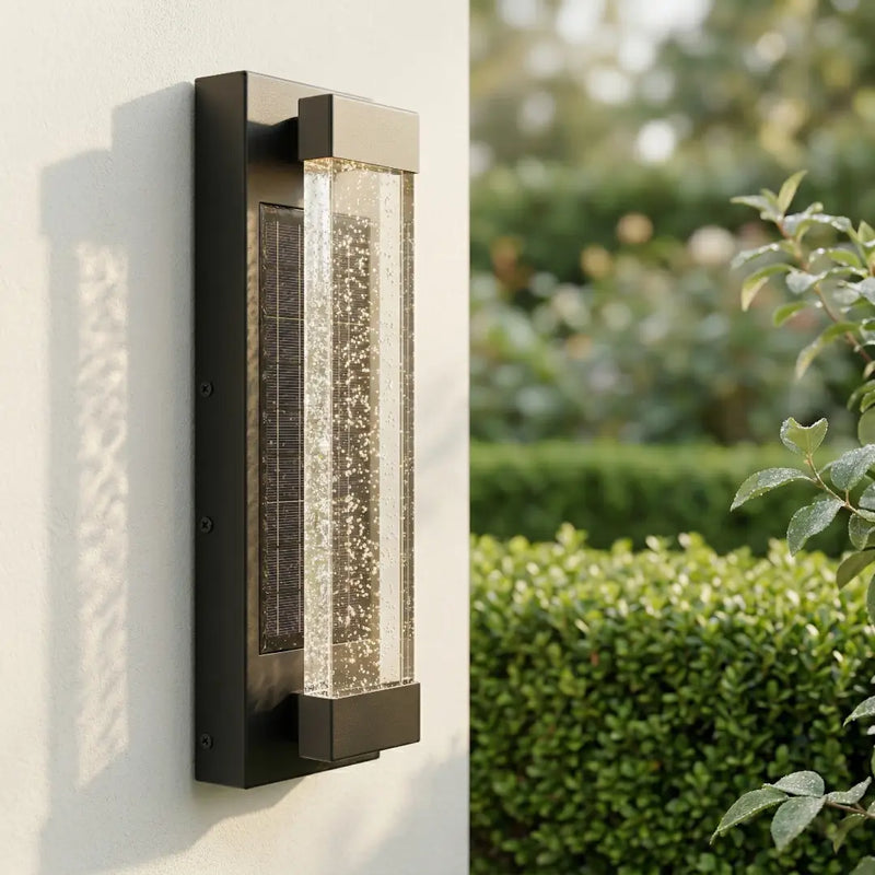 Modern outdoor wall light fixture on a white wall with greenery in the background