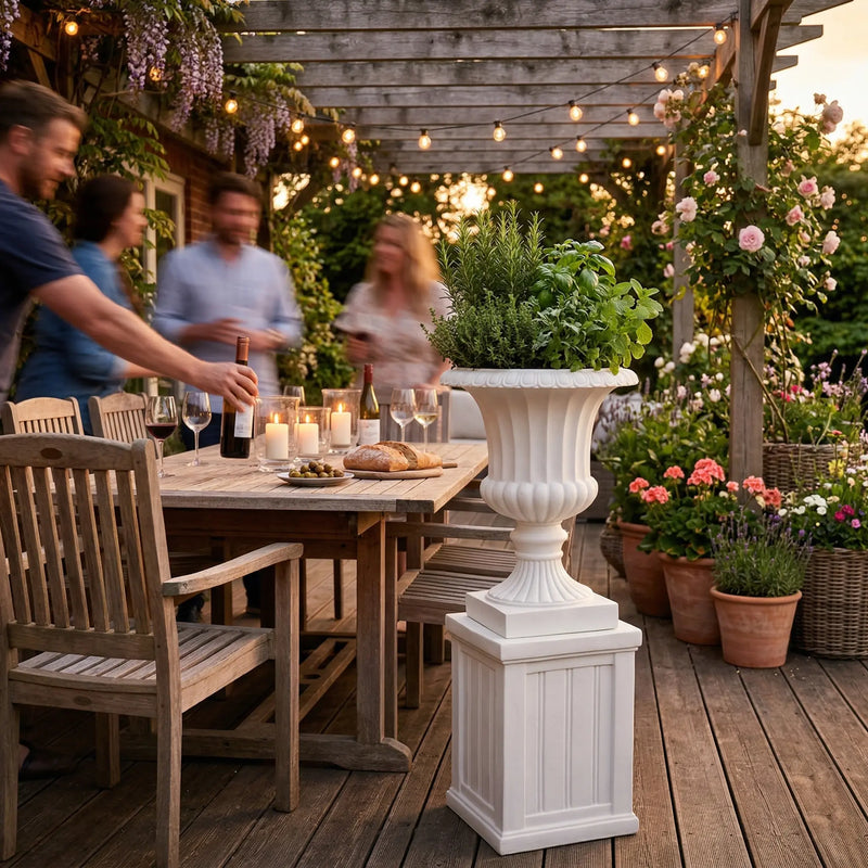 Outway F005 F006 Petra roman sandstone planter pedestal on timber deck beside outdoor dining table string lights dusk herbs