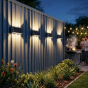 Tenox PT0716 solar wall lights mounted on grey Colorbond fence, casting warm up-and-down glow at dusk, Australian backyard BBQ setting