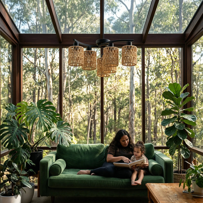 Woman and child reading on a green couch in a room with large windows and plants.