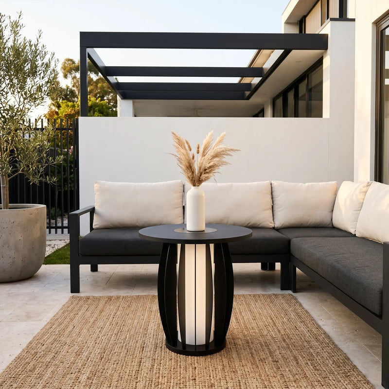 Outdoor patio with gray sectional sofa, black and white table, and decorative vase.