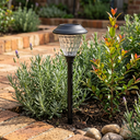 Close-up of solar pathway light with textured crystal glass lens nestled among lavender and rosemary, highlighting its elegant design and seamless integration into garden beds — perfect for enhancing floral landscapes with ambient, low-profile illumination.