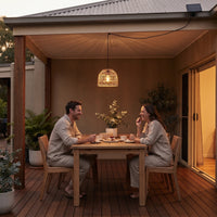 Couple enjoying dessert under PT0913 pendant on covered deck at twilight, smiling as they share cake — cozy evening ambiance with soft woven glow and remote-controlled brightness settings.