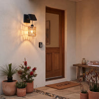 PT0909 solar wall sconce flanking wooden front door, illuminating entryway with textured glow; terracotta pots with kangaroo paw plants and “G’DAY” mat enhance welcoming curb appeal — no wiring needed.