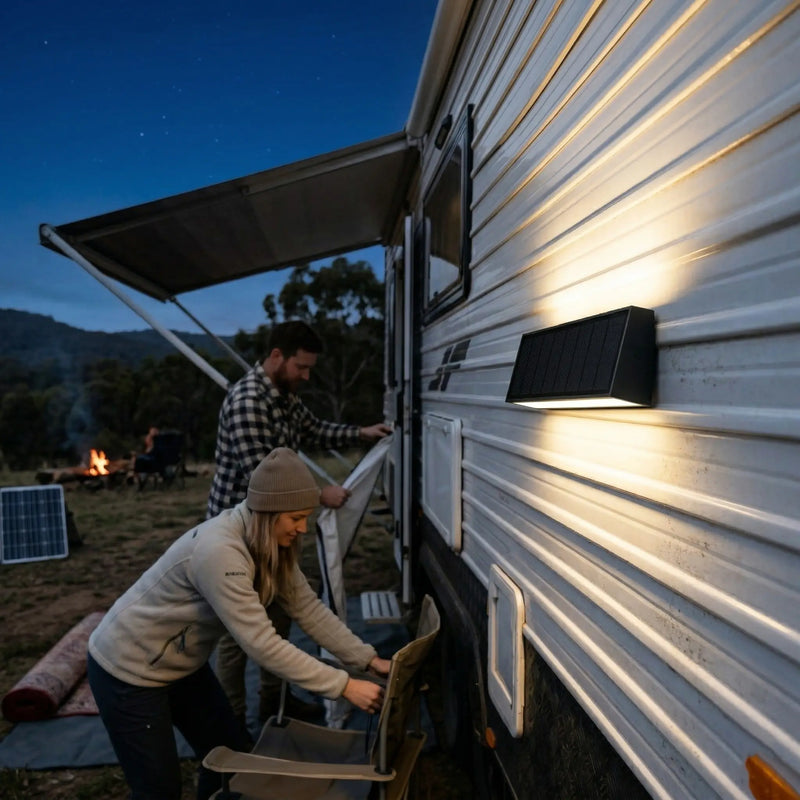 Tenox PT0716 solar wall light installed on caravan exterior at night, couple setting up campsite under starry sky in Australian bush
