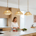 Three Handwoven HAIKU solar pendant lights suspended over a modern kitchen island, showcasing the natural woven bamboo texture and warm ambient lighting indoors.