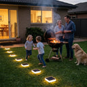 Family grilling outdoors with solar lights on the grass