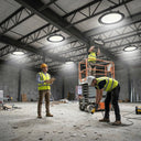 Construction workers installing multiple UFO LED high bay lights on warehouse ceiling using scissor lift platform