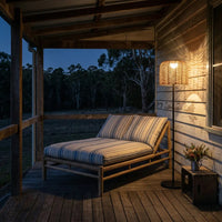 At night, the PT0908 Solar Rattan Floor Lamp illuminates a wooden porch, casting a warm glow and intricate woven shadows on the wall and striped lounge chair, creating a serene outdoor retreat atmosphere.