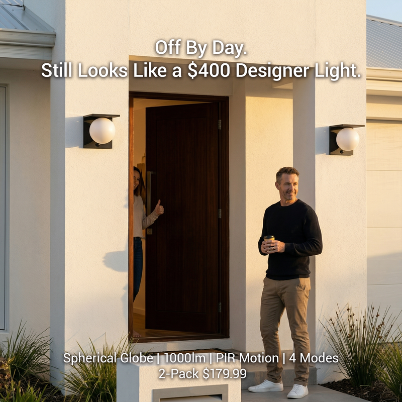 Lumora Solar globe wall lights installed either side of modern front door at golden hour, man holding coffee smiling outside, woman giving thumbs up from doorway, text overlay: Off By Day. Still Looks Like a $400 Designer Light. 