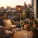 Balcony scene with LunaBeam lamp beside wicker chair and potted plants — city skyline backdrop highlights urban adaptability, featuring 3000K/4000K/6000K color temp and USB backup charging.