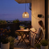 Woman reading book under PT0913 pendant on balcony at night, city lights in background — serene urban retreat vibe with gentle pulse mode and USB backup power for cloudy days.