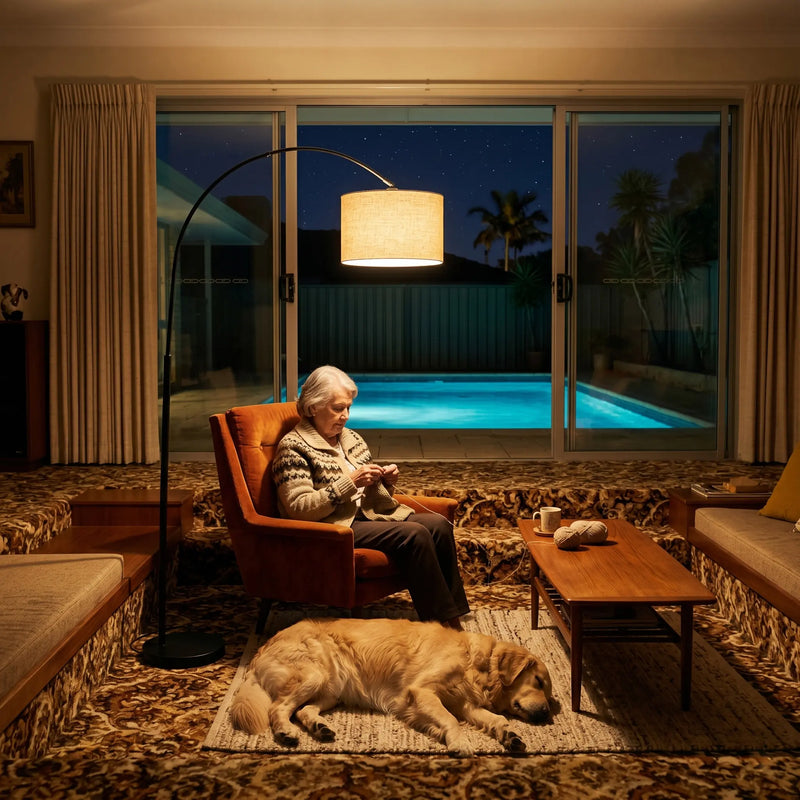 Woman sitting in a chair by a pool at night with a dog lying on the floor.