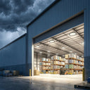 Multiple UFO LED high bay lights illuminating large open warehouse with forklift during stormy weather at night