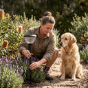 Woman adjusting a solar lamp in a garden with a dog sitting nearby