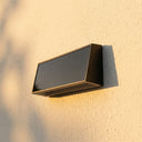 Tenox PT0716 solar wall light mounted on rendered wall in daylight, showing slim 44mm depth profile and integrated solar panel
