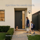 Serra solar wall light installed beside front door, mother and child arriving home at dusk, text overlay: Light Where You Actually Need It, 180 degree adjustable angle, PIR motion sensor