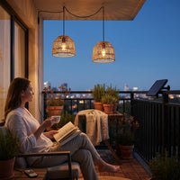 Woman reading on balcony under two PT0914 pendants at night, city skyline in background — urban retreat vibe with remote-controlled breathing mode and steady light options.