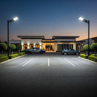 Two OUTWAY Nexa T007 solar street lights providing bright security lighting for a commercial car park and office building entrance at night.