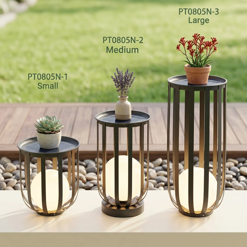 Set of three decorative tables with plants and lights on a garden setting