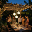 Three warm white solar hanging globe lights illuminating an outdoor dinner party under a wooden pergola.