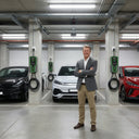 Man standing in a parking garage with electric cars and charging stations.