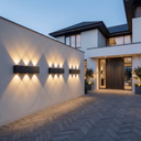 Modern house exterior with wall-mounted lights and a well-lit entrance.Modern solar LED wall light.