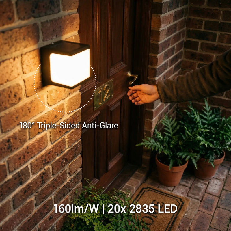 
PT0711 Cube solar wall light mounted beside a brick front door at night, with dotted circle callout showing 180° Triple-Sided Anti-Glare diffusion. Text overlay: 160lm/W | 20x 2835 LED.