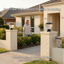 OUTWAY Priva PT0111 solar pillar cap lights on twin white brick entrance pillars of an Australian suburban home at golden hour with a woman watering plants and text overlay Your Pillar Light Doesnt Have to Be Boring Pumpkin Design 3 Colours All Night Auto Dusk-Dawn