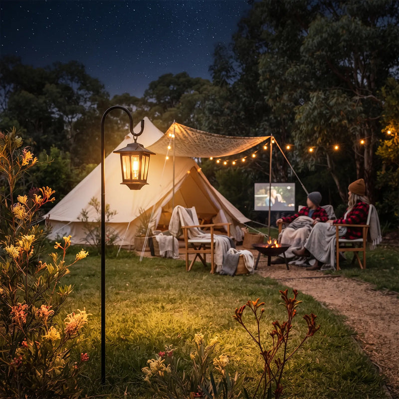 HeritageHook Solar Lantern glowing beside glamping tent with couple watching outdoor movie, demonstrating its versatility for camping, backyard cinema nights, and rustic-chic outdoor entertaining.