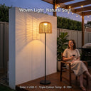 The PT0908 Solar Floor Lamp glowing on an outdoor terrace with a smiling woman holding a glass of wine, set against a backdrop of string lights and plants, with the text 'Woven Light. Natural Soul.' emphasizing its natural woven beauty and triple color temperature features.