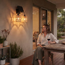 Woman relaxing on deck under Kasa Duo’s warm illumination — demonstrates lifestyle integration with wine and plants, emphasizing comfort and ambient control via single-button mood switching.