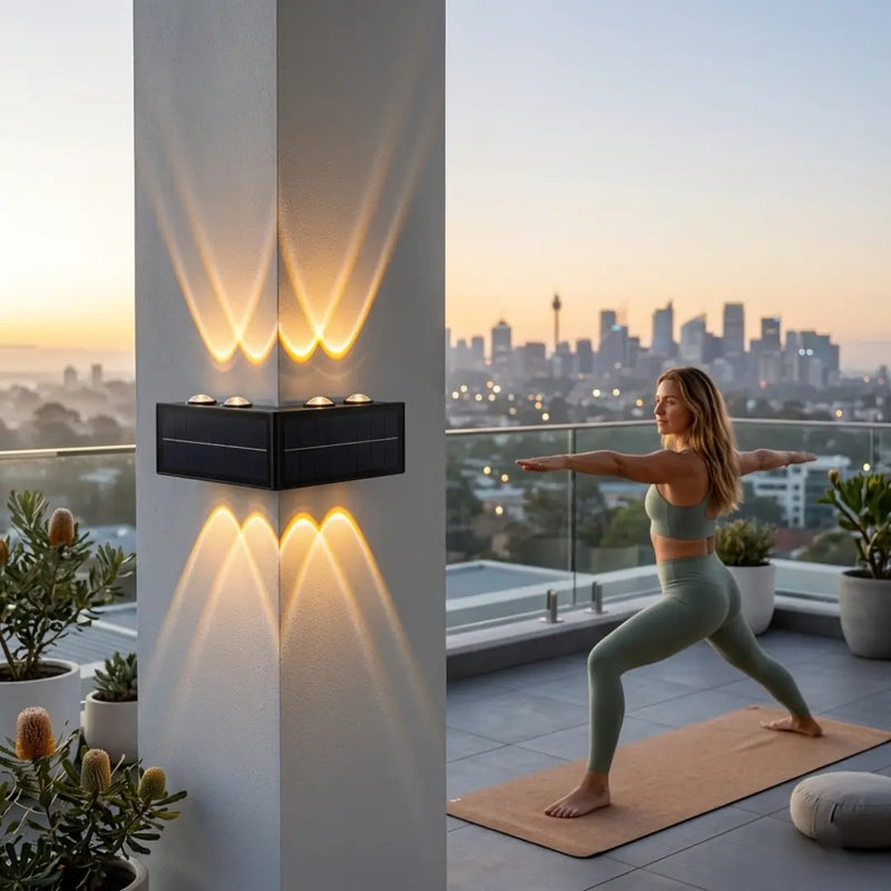 A woman practicing yoga in a warrior pose on a high-rise balcony at sunrise, with the Grivo solar corner light mounted on a pillar casting warm up and down lighting, set against a backdrop of the Sydney city skyline.